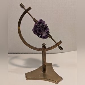 A golden-toned sphere holder caliper stand with an amethyst crystal cluster.